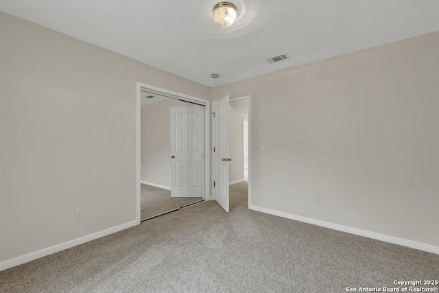 carpeted spare room featuring visible vents and baseboards