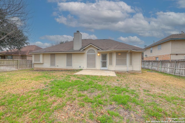 back of property featuring a patio area, a fenced backyard, a chimney, and a yard