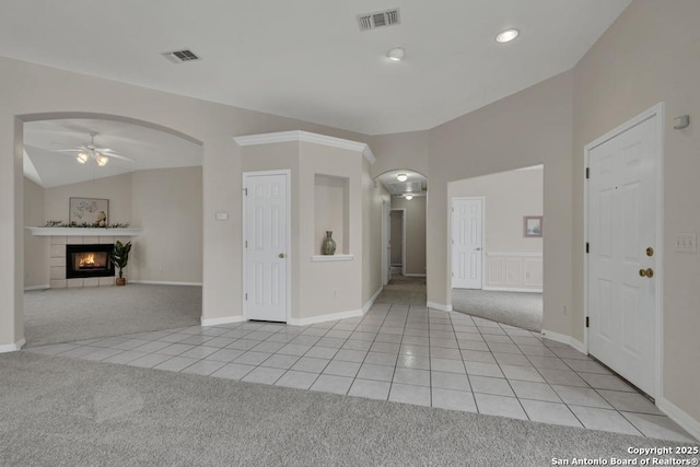 interior space featuring light carpet, light tile patterned flooring, a tile fireplace, and visible vents