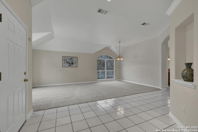 empty room with arched walkways, light colored carpet, visible vents, light tile patterned flooring, and vaulted ceiling