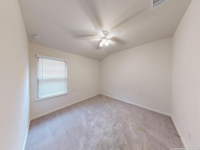 empty room with ceiling fan, light colored carpet, lofted ceiling, and a textured ceiling