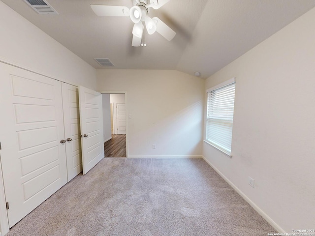 unfurnished bedroom featuring vaulted ceiling, carpet flooring, ceiling fan, and a closet