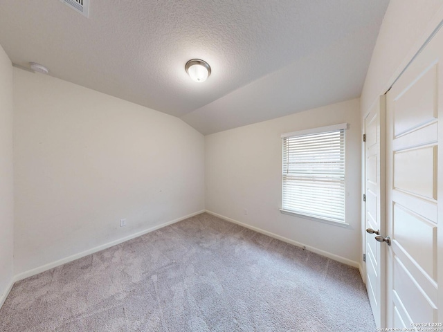 unfurnished room featuring light colored carpet, lofted ceiling, and a textured ceiling