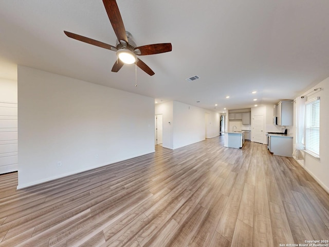 unfurnished living room featuring ceiling fan, sink, and light hardwood / wood-style floors