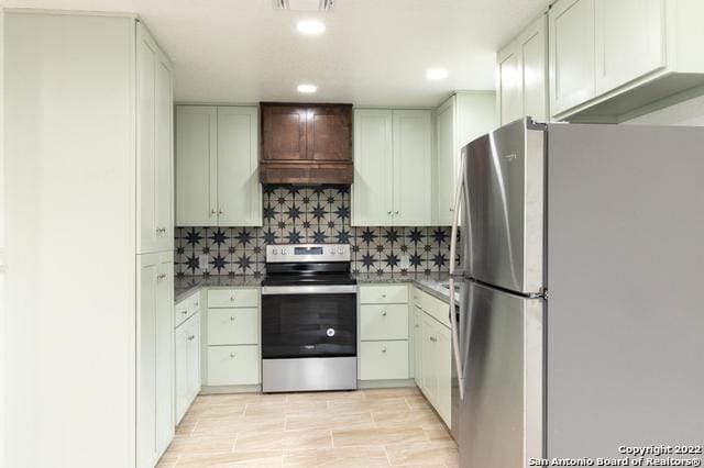 kitchen featuring white cabinetry, tasteful backsplash, stainless steel appliances, and custom range hood