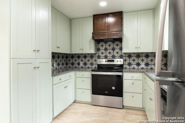 kitchen with white cabinetry, dark stone countertops, backsplash, and electric range