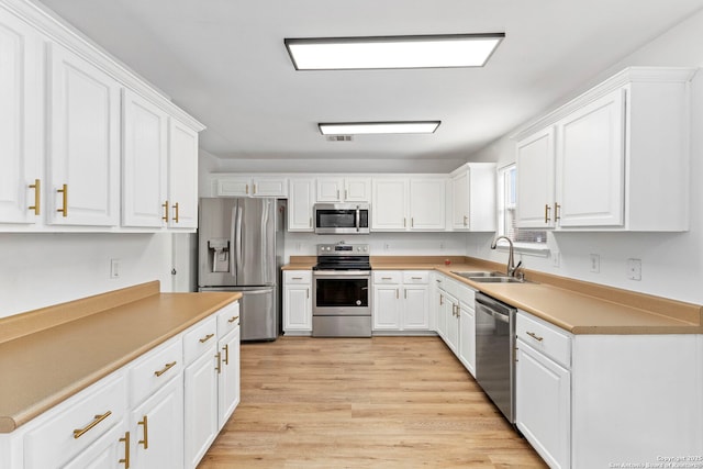 kitchen featuring sink, light hardwood / wood-style floors, white cabinets, and appliances with stainless steel finishes