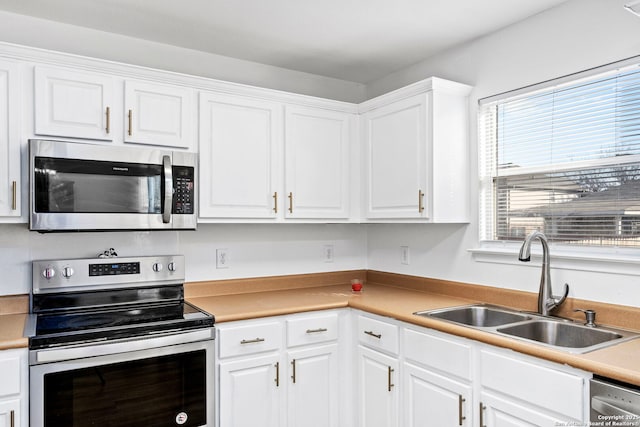 kitchen with stainless steel appliances, sink, and white cabinets