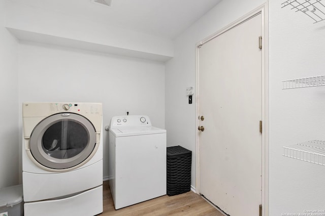 laundry area featuring washer and dryer and light hardwood / wood-style flooring