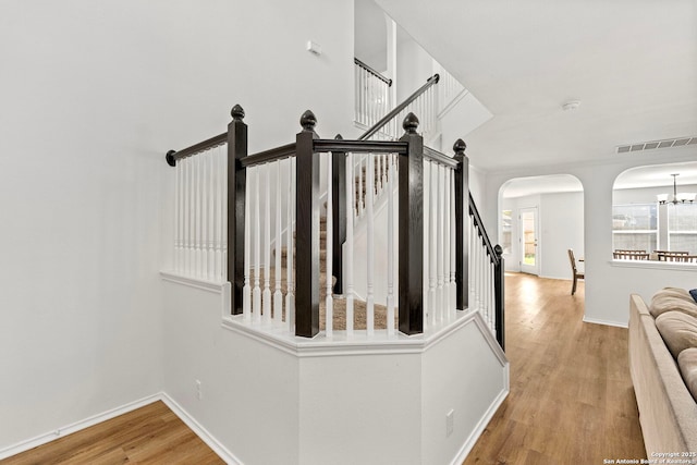 stairs featuring wood-type flooring and a chandelier