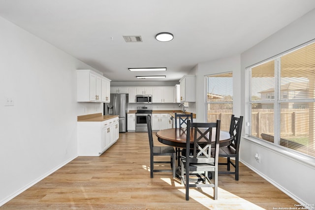 dining space with sink and light wood-type flooring