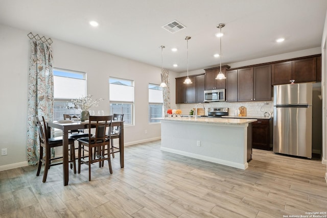 kitchen with dark brown cabinetry, visible vents, appliances with stainless steel finishes, light wood-type flooring, and tasteful backsplash