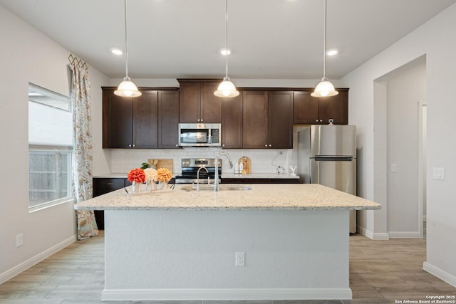 kitchen featuring stainless steel appliances, dark brown cabinetry, a sink, and tasteful backsplash