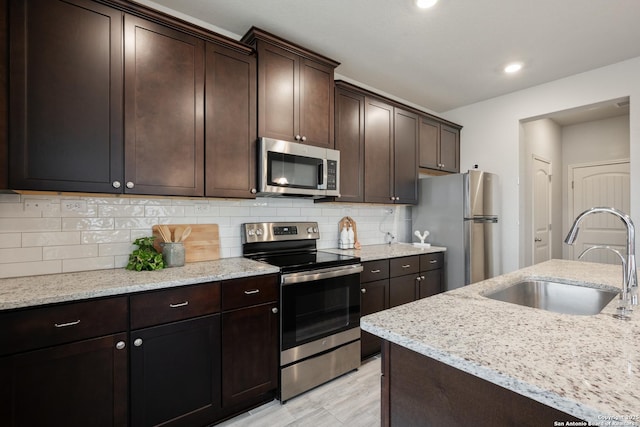 kitchen with backsplash, dark brown cabinets, stainless steel appliances, and a sink