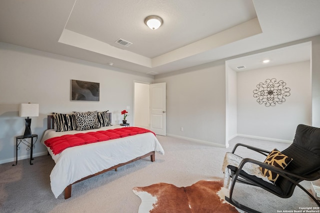 carpeted bedroom with baseboards, visible vents, and a tray ceiling