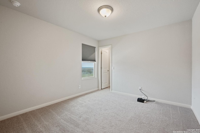 carpeted spare room with a textured ceiling and baseboards