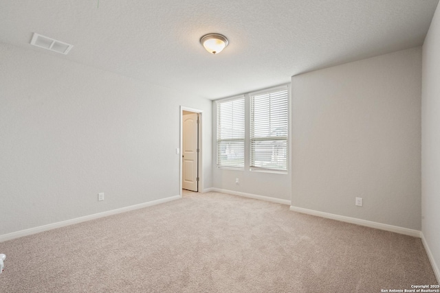 empty room with light carpet, baseboards, visible vents, and a textured ceiling