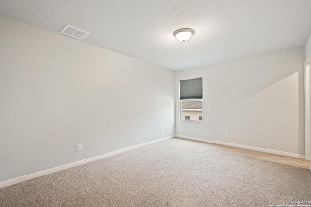 carpeted spare room featuring a textured ceiling, visible vents, and baseboards