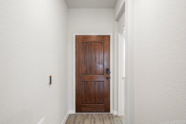 doorway to outside with light wood-type flooring and baseboards