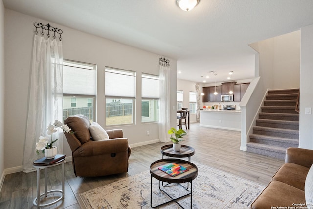 living area with light wood-style flooring, stairway, baseboards, and recessed lighting