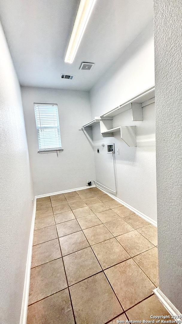 laundry area featuring gas dryer hookup, washer hookup, electric dryer hookup, and light tile patterned floors