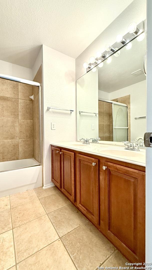 bathroom featuring tiled shower / bath, vanity, tile patterned flooring, and a textured ceiling