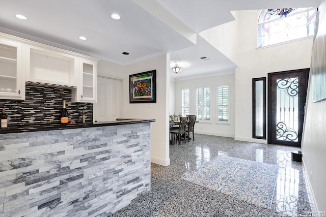 interior space with ornamental molding, white cabinets, and decorative backsplash