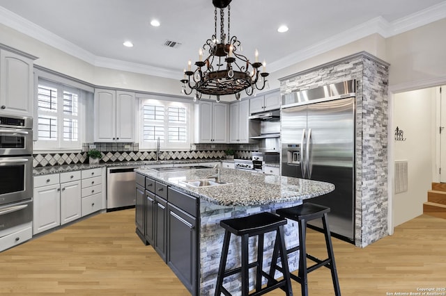 kitchen featuring sink, dark stone countertops, a kitchen breakfast bar, stainless steel appliances, and an island with sink