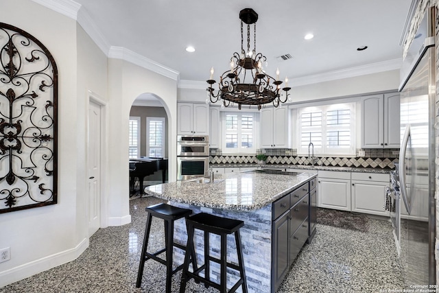 kitchen featuring gray cabinets, tasteful backsplash, a kitchen island, and crown molding