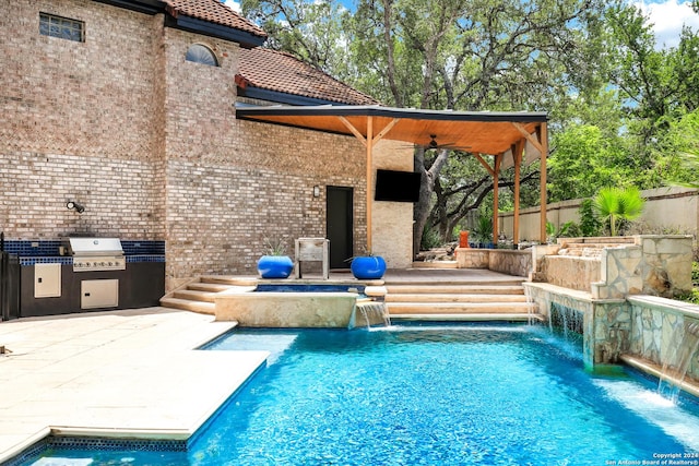 view of pool with a patio, a grill, exterior kitchen, pool water feature, and ceiling fan