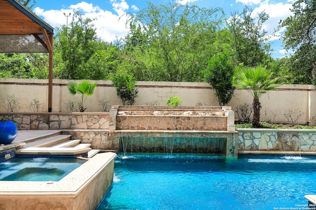 view of swimming pool with pool water feature and an in ground hot tub