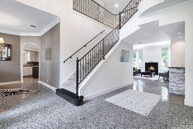 staircase with crown molding and a towering ceiling