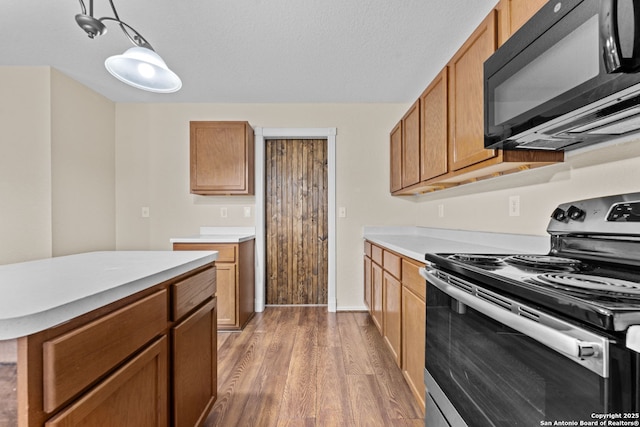 kitchen with hanging light fixtures, electric range, and wood-type flooring