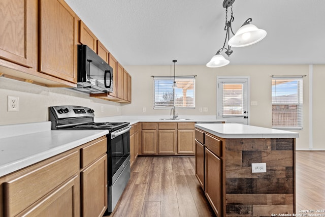 kitchen featuring sink, stainless steel range with electric stovetop, a kitchen island, pendant lighting, and hardwood / wood-style floors