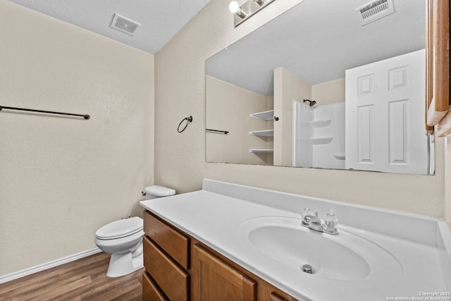 bathroom featuring wood-type flooring, a shower, vanity, and toilet