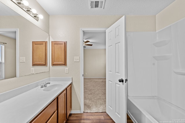 bathroom featuring hardwood / wood-style flooring, ceiling fan, vanity, and a textured ceiling