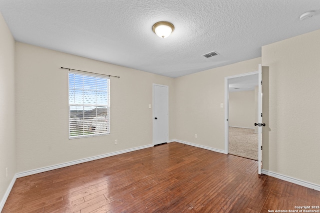 empty room featuring wood-type flooring and a textured ceiling