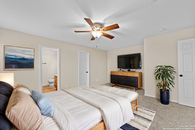 bedroom featuring ceiling fan, light colored carpet, connected bathroom, and a textured ceiling