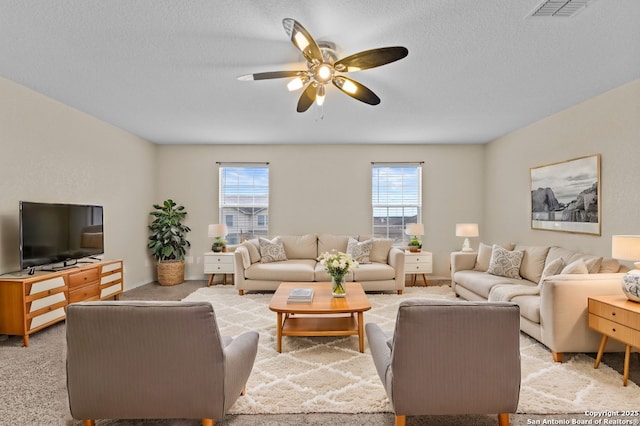 living room with ceiling fan, light colored carpet, and a textured ceiling