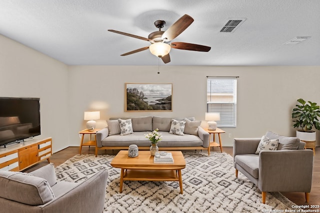 living room featuring hardwood / wood-style flooring, a textured ceiling, and ceiling fan