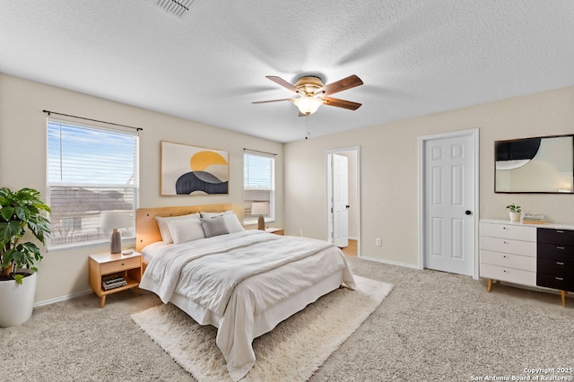 bedroom with ceiling fan, light colored carpet, and a textured ceiling