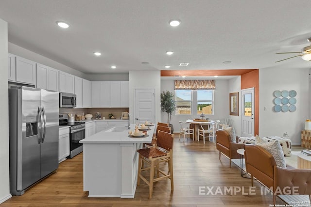 kitchen featuring sink, a breakfast bar, appliances with stainless steel finishes, white cabinetry, and a kitchen island with sink