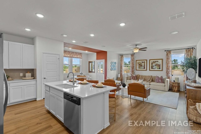 kitchen with white cabinetry, dishwasher, sink, an island with sink, and light hardwood / wood-style floors