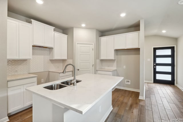 kitchen with sink, dark hardwood / wood-style flooring, a kitchen island with sink, and white cabinets