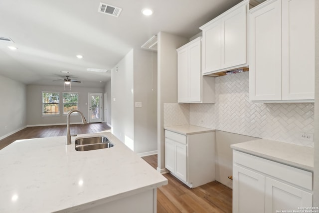 kitchen featuring sink, white cabinets, a center island, light stone counters, and light hardwood / wood-style floors