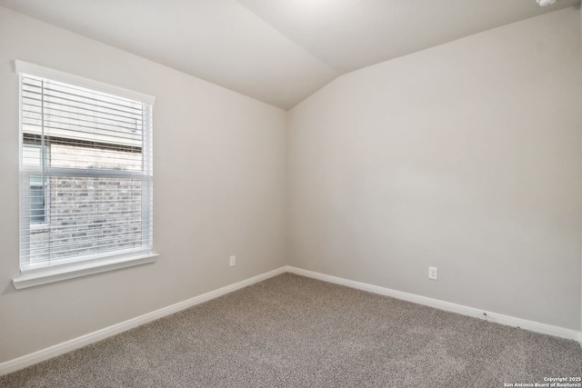 empty room with vaulted ceiling and carpet flooring