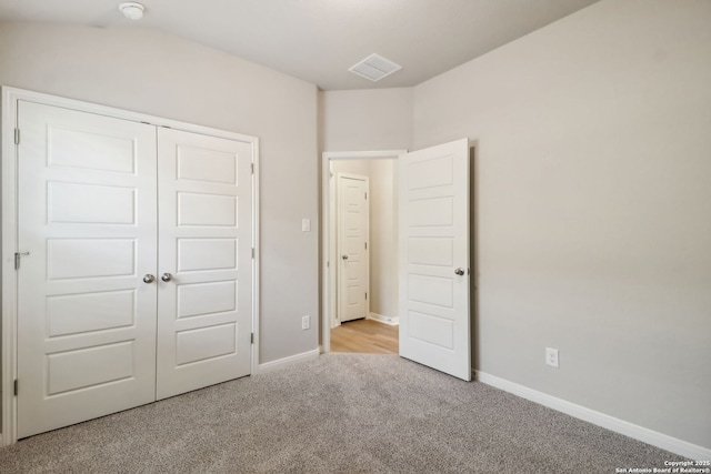 unfurnished bedroom with light colored carpet and a closet