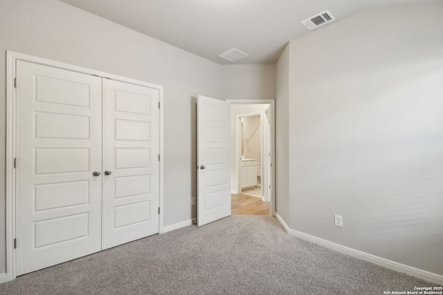 unfurnished bedroom with light colored carpet and a closet