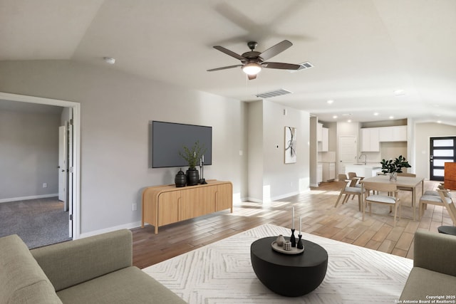 living room with lofted ceiling, sink, light hardwood / wood-style flooring, and ceiling fan