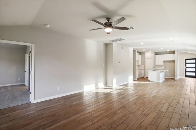 unfurnished living room featuring lofted ceiling, sink, wood-type flooring, and ceiling fan